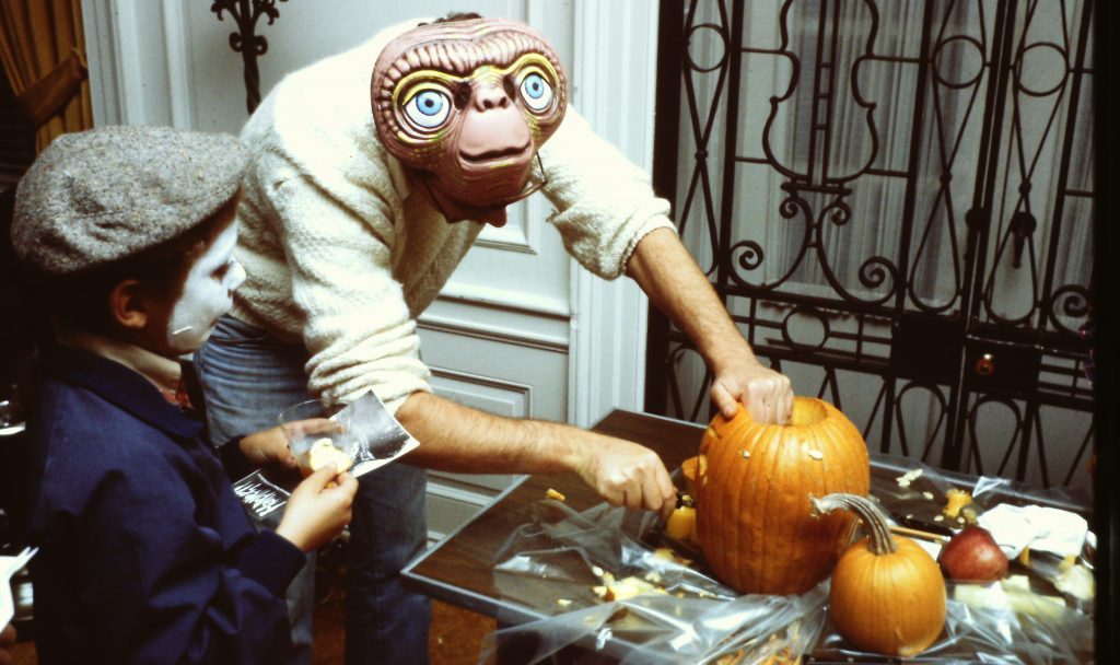 Jeff Oshins, con una máscara de E. T., talla una calabaza de Halloween mientras un niño observa en la Library of Congress, en 1982.