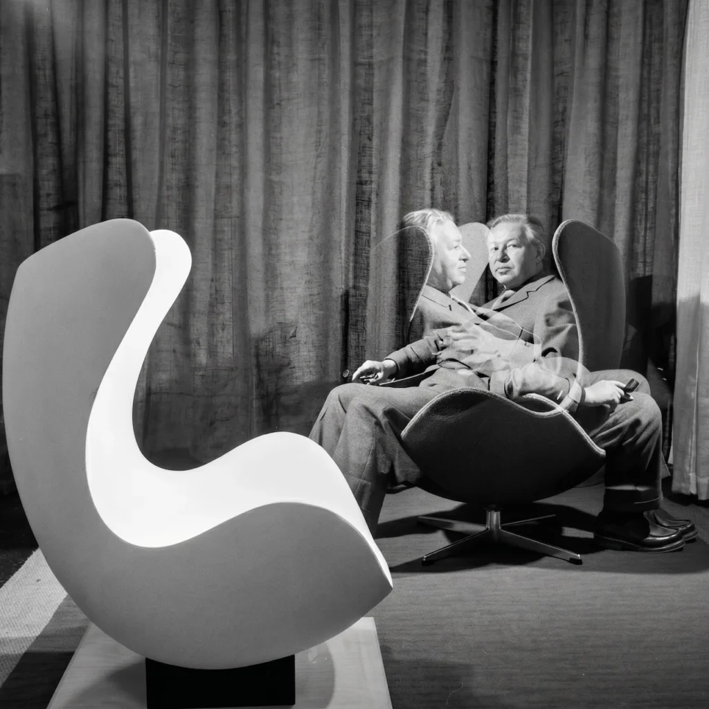 El diseñador Arne Jacobsen sentado en su butaca Egg en 1958, ejemplificando la ergonomía y estética funcional del diseño nórdico para el Hotel Royal de Copenhague.