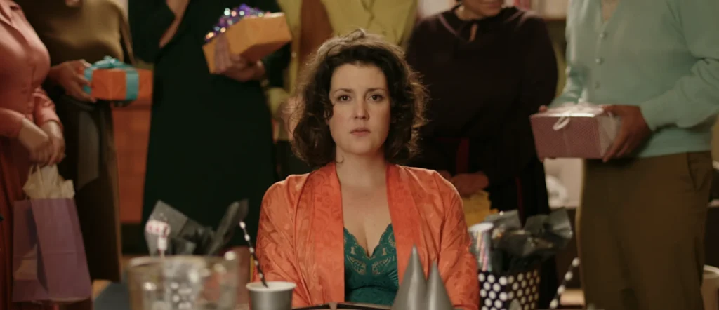 Mary (Melanie Lynskey) rodeada por la etiqueta burguesa en el corto de Annie Clark para XX, simbolizando el búnker de la negación social.