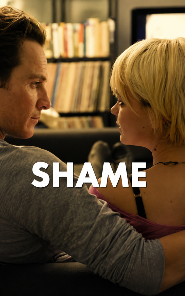 El actor Michael Fassbender abraza a la actriz Carey Mulligan sentados en un sillón en una escena de la película Shame de 2011 sobre adicción al sexo.