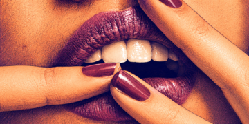 Cabinas sexuales en CDMX: qué son, cómo funcionan y qué ocurre dentro Primer plano conceptual de labios con labial morado brillante y uñas pintadas, representando la sensualidad, el erotismo y el anonimato dentro de las cabinas sexuales en CDMX.