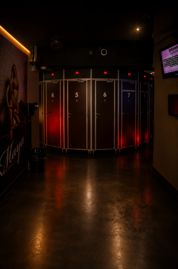 Pasillo interior de un establecimiento para adultos en CDMX con cabinas privadas numeradas e iluminadas con luces LED rojas.