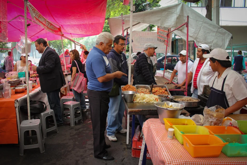 Puestos de comida tradicional y productos frescos en el tianguis de Sullivan, Ciudad de México, operando como espacio de cohesión social frente a la gentrificación.