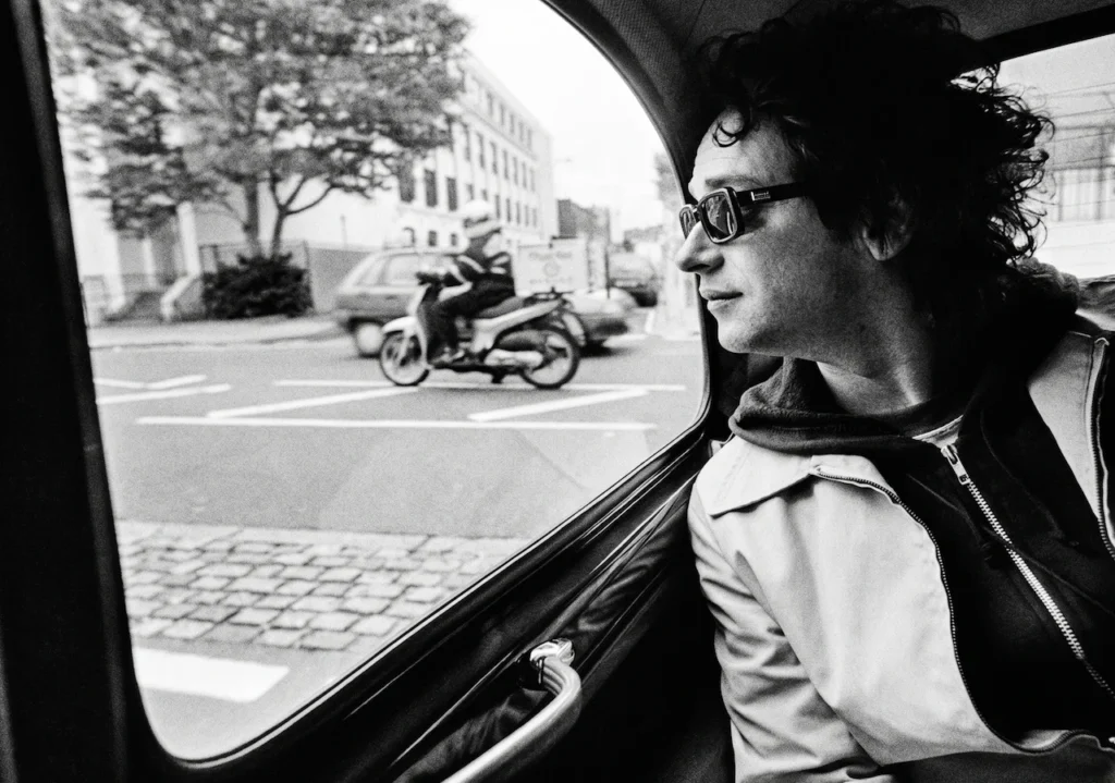 Gustavo Cerati mirando por la ventana de un taxi en Londres, capturando  la introspección de su etapa solista en Abbey Road.