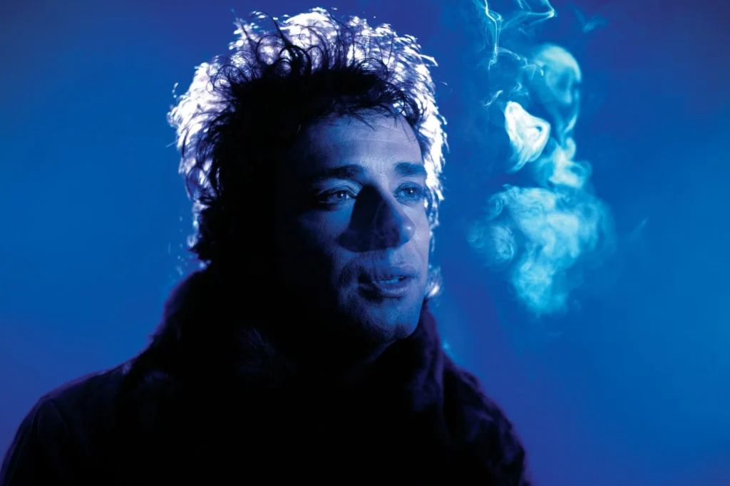 Retrato de Gustavo Cerati con iluminación azul y atmósfera de humo, representando la sofisticación sonora y visual de su álbum Bocanada.