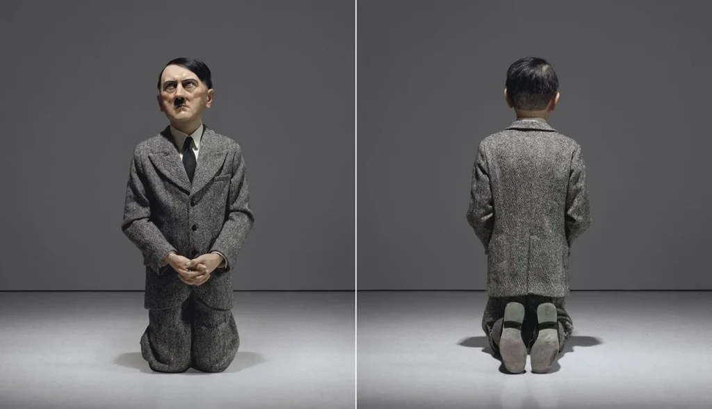 Escultura hiperrealista de tamaño infantil que representa a Adolf Hitler de rodillas en actitud de oración, correspondiente a la obra Him de Maurizio Cattelan.