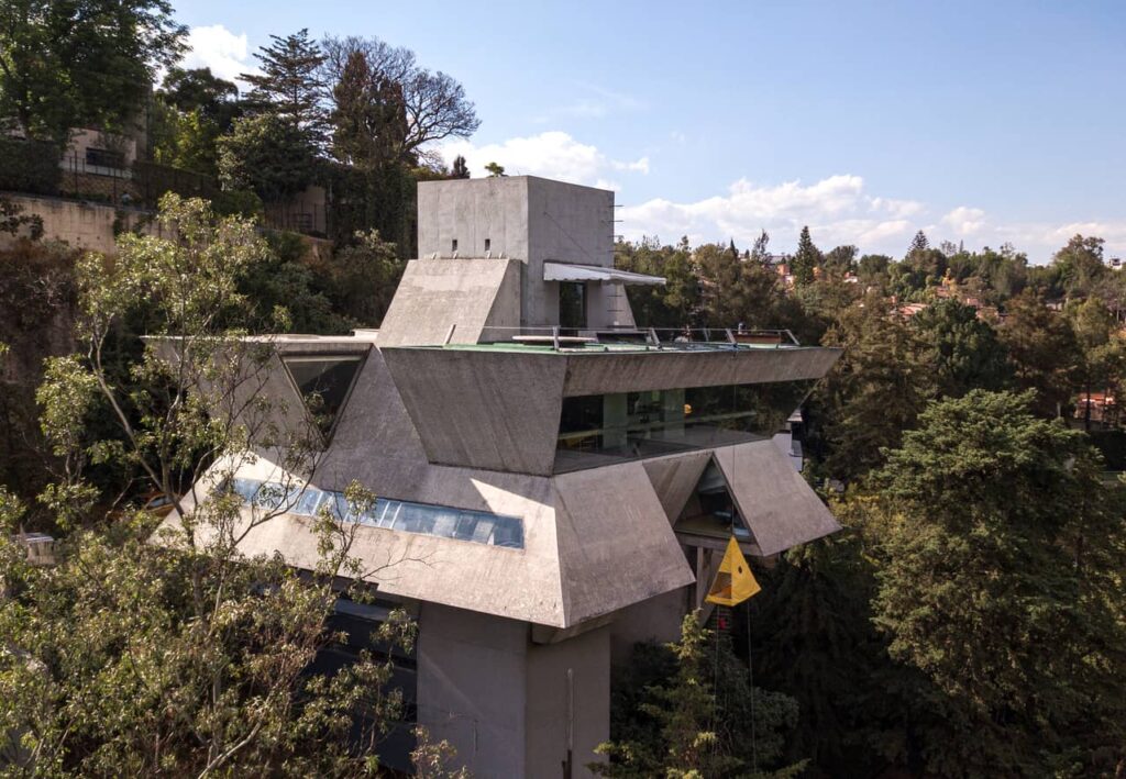 Vista aérea exterior de la Casa Praxis, un taller y vivienda de arquitectura brutalista construido en concreto expuesto flotando sobre el bosque de Bosques de las Lomas en la Ciudad de México.