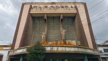 Cines abandonados de la CDMX: nostalgia en el espacio público Fachada abandonada de estilo Art Déco del antiguo Cine Ópera en la colonia San Rafael de la Ciudad de México con dos grandes estatuas de piedra en la entrada, bajo un cielo nublado.