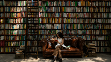 Librerías baratas en CDMX: guía para encontrar joyas sin gastar mucho Una mujer joven lee un libro sentada en un sillón de piel marrón frente a una enorme estantería repleta de libros en una librería económica de viejo.