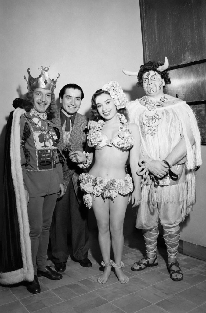 Fotografía histórica en blanco y negro del diseñador Ramón Valdiosera posando junto a actores caracterizados con vestuarios de época y de fantasía mitológica