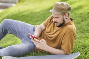 Escapadas Estacionales: Las Mejores Actividades de Ocio Para Cada Época del Año relaxed-man-lying-on-the-grass-using-the-phone