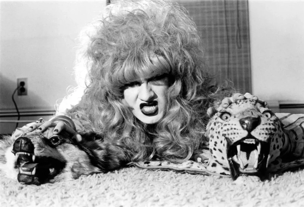 Jayne County posando con una expresión feroz junto a cabezas de animales de peluche, capturando la estética teatral y provocadora del proto-punk de los setenta.