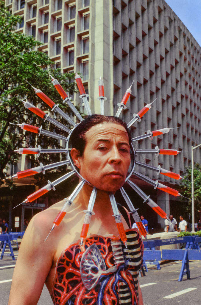 Pedro Lemebel con corona de jeringas y órganos pintados en el torso durante Alacranes en la marcha, Nueva York, 1994.