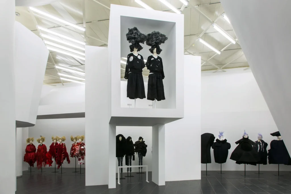 Vista de la arquitectura expositiva en la muestra 'Rei Kawakubo/Comme des Garçons: Art of the In-Between' en el Metropolitan Museum of Art (The Met), 2017. La instalación destaca maniquíes vestidos con piezas icónicas deconstruidas, dispuestas en una estructura laberíntica diseñada por la propia Kawakubo para romper con las convenciones museísticas tradicionales.