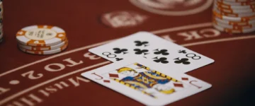 Close-up study of a strategic card arrangement on a red casino table with poker chips, illustrating an editorial guide on digital gaming probabilities and risk management.