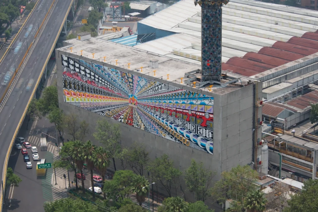 Mural monumental de Pedro Friedeberg en la fábrica de la Cervecería Corona, integración de arte surrealista en espacio industrial.