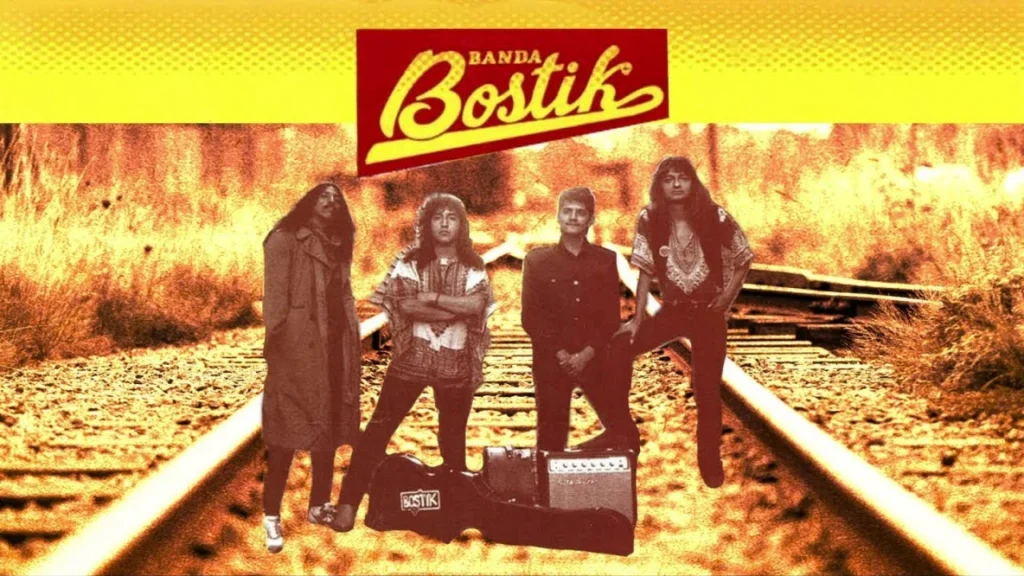 Integrantes originales de la Banda Bostik posando sobre las vías del tren en una fotografía de archivo en tonos sepia.
