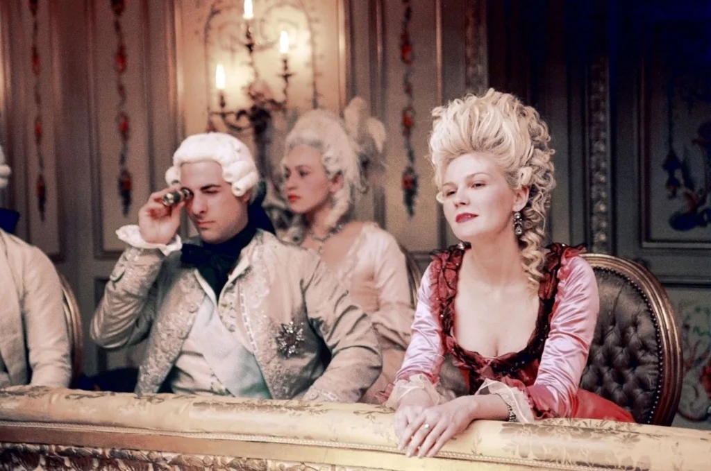 Kirsten Dunst como María Antonieta en la ópera, mostrando el maquillaje blanco de cerusa (blanc) y lunares (mouches) característicos de la corte de Versalles en el siglo XVIII.