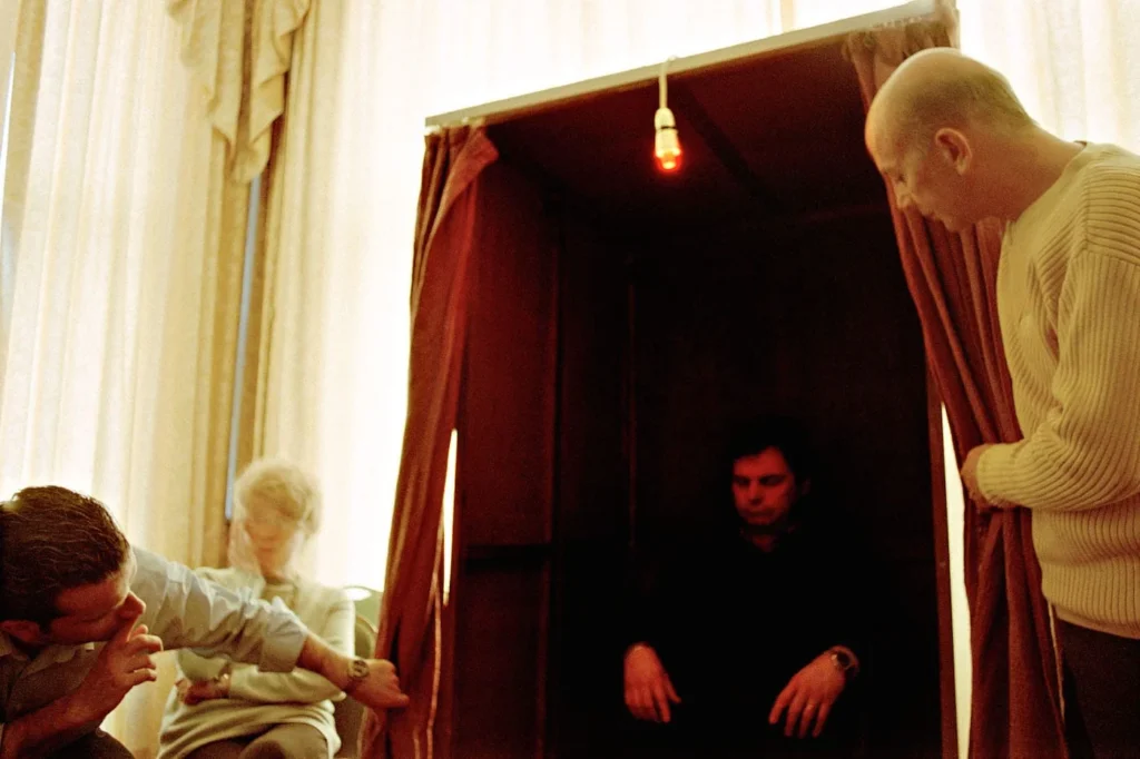 Retrato de una sesión espiritista capturado por Shannon Taggart, mostrando el uso de luz y movimiento para registrar lo espiritual.