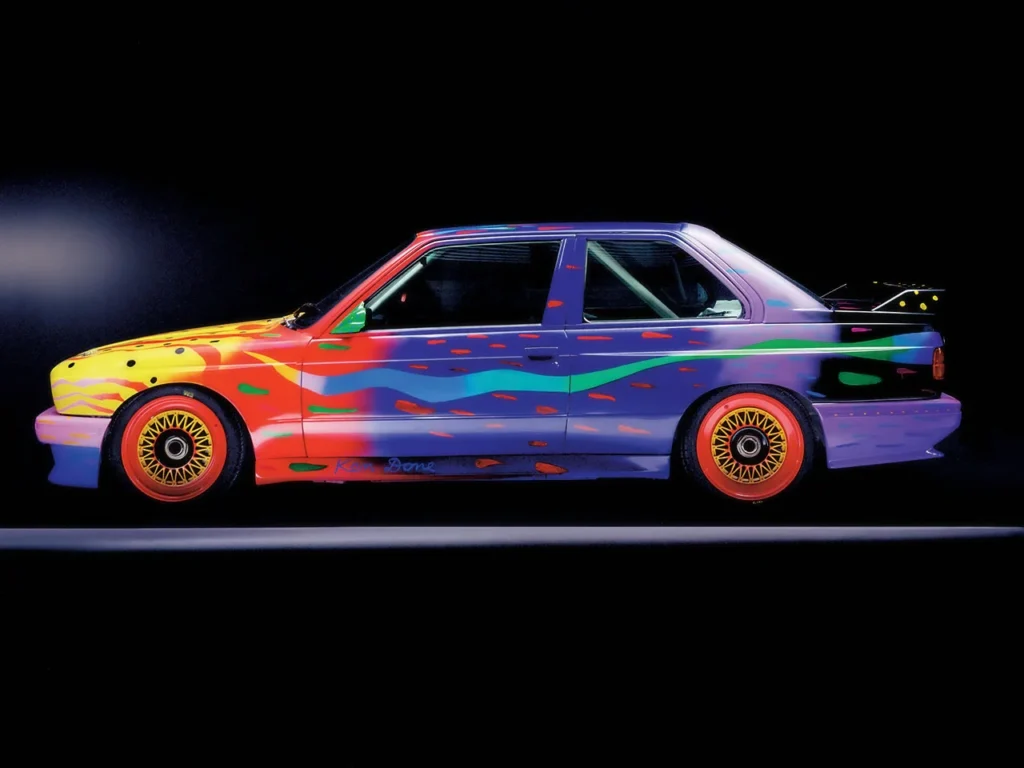 Vista lateral de estudio del BMW M3 Group A Art Car diseñado por Ken Done (1989), mostrando la explosión de colores y patrones abstractos sobre la carrocería de competición.