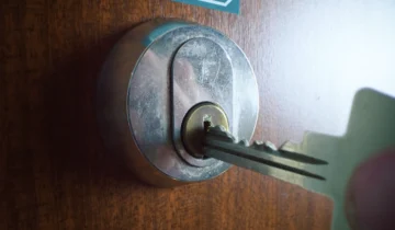 Detalle técnico de un cilindro de alta seguridad ASSA instalado en puerta de madera, mostrando la precisión del sistema de cierre.