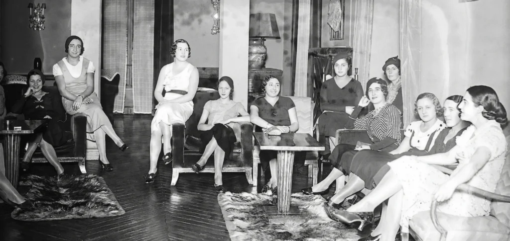 Grupo de mujeres intelectuales y artistas del Lyceum Club de París reunidas en un salón de la Rive Droite, representando la profesionalización y resistencia de la mujer en la vanguardia de principios del siglo XX.