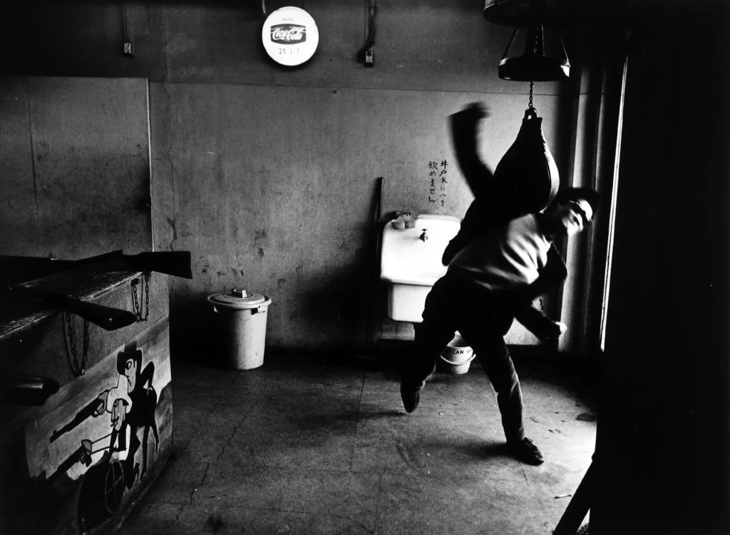 Fotografía de Takuma Nakahira de un hombre entrenando boxeo, capturando el estilo disruptivo y la tensión social de la revista Provoke.