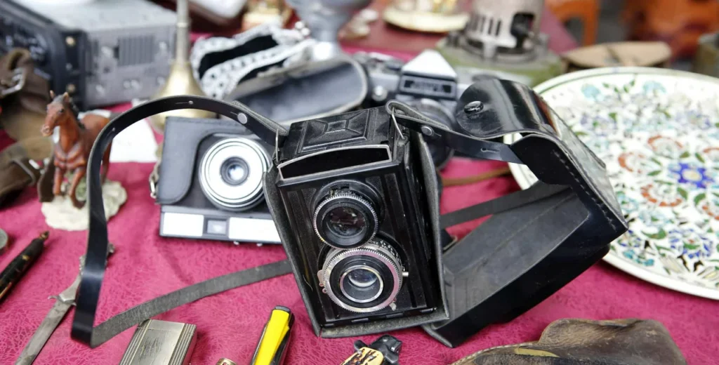 Cámara fotográfica antigua de doble lente y estuche de cuero negro en un puesto de antigüedades de la CDMX.