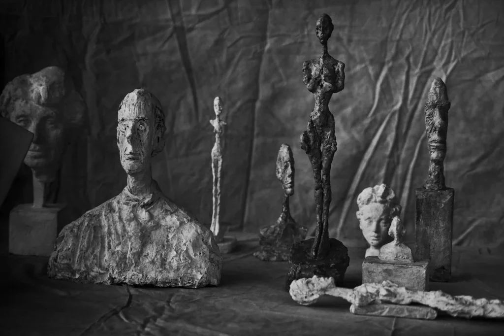 Fotografía en blanco y negro del estudio de Alberto Giacometti, mostrando una acumulación de esculturas filiformes y bustos de yeso, ejemplificando la reducción del ser y la resistencia existencial de la Fondation Giacometti.