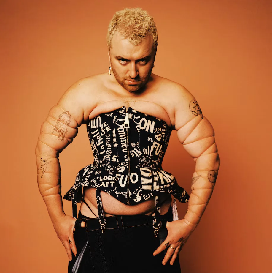 Plano medio de un torso masculino musculoso con un corsé negro minimalista de Michaela Stark, resaltando la tensión de la prenda sobre la anatomía y el contraste sobre fondo negro.