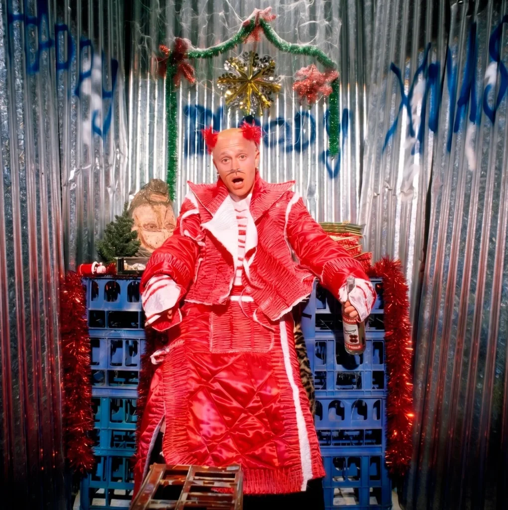 Keith Flint en un entorno industrial con estética de búnker y vestuario rojo vibrante, reflejando la atmósfera claustrofóbica de la era 'The Fat of the Land'.