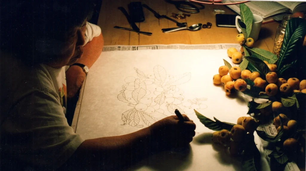La artista Ruth Asawa dibujando elementos botánicos en su mesa de trabajo, ilustrando su filosofía de que el dibujo es la base de la independencia intelectual y la observación atenta.