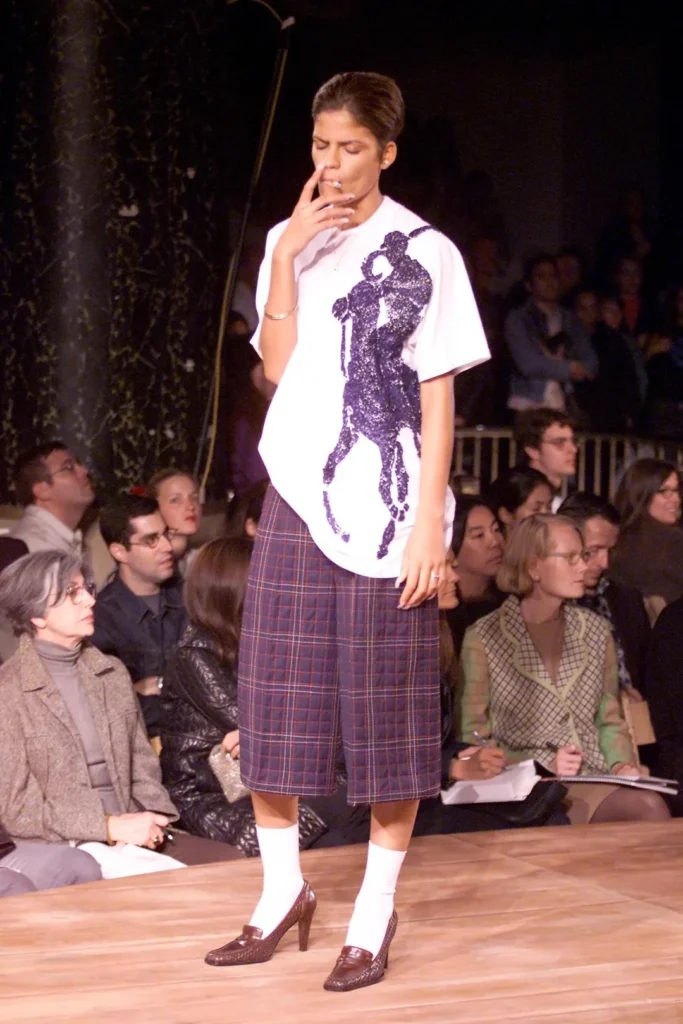 Modelo en pasarela vistiendo una camiseta de Ralph Lauren intervenida por Miguel Adrover, como parte de su crítica a la propiedad intelectual de las marcas de lujo.