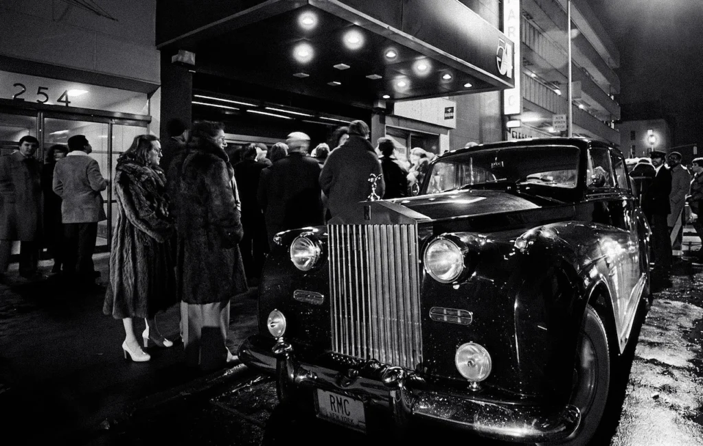 Un Rolls Royce estacionado frente a la entrada de Studio 54 en Nueva York, con la multitud acumulada esperando la validación del algoritmo humano de Steve Rubell.