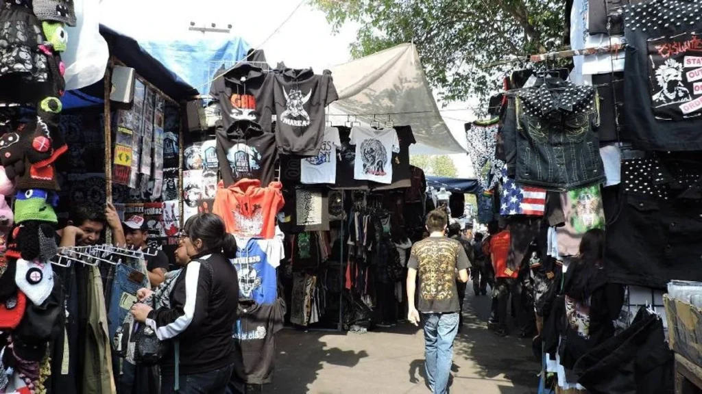 Puestos de ropa y sudaderas de bandas de rock y metal en el pasillo principal del Tianguis Cultural del Chopo en la CDMX.