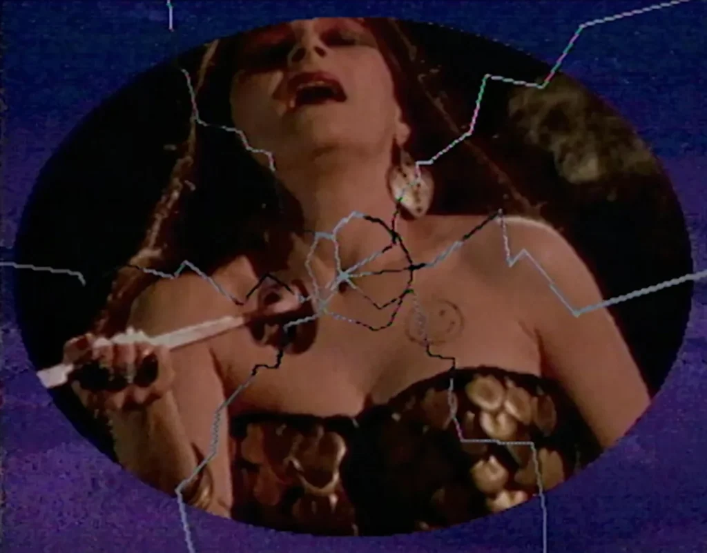 Fotograma circular del videoarte Corazón sangrante de Ximena Cuevas mostrando a una mujer con un cuchillo apuntando a su pecho con un efecto visual de vidrio roto.