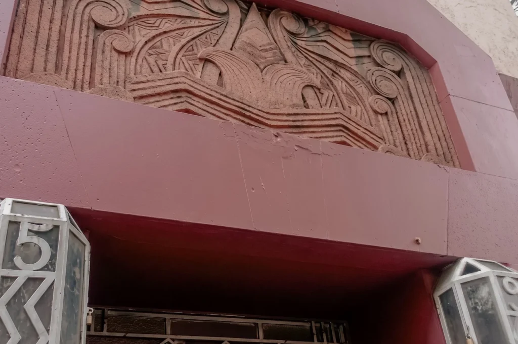 Detalle decorativo de bajorrelieve en la fachada de una casa histórica en las colonias Roma o Juárez, mostrando el deterioro de la piedra y elementos originales de diseño Art Nouveau.