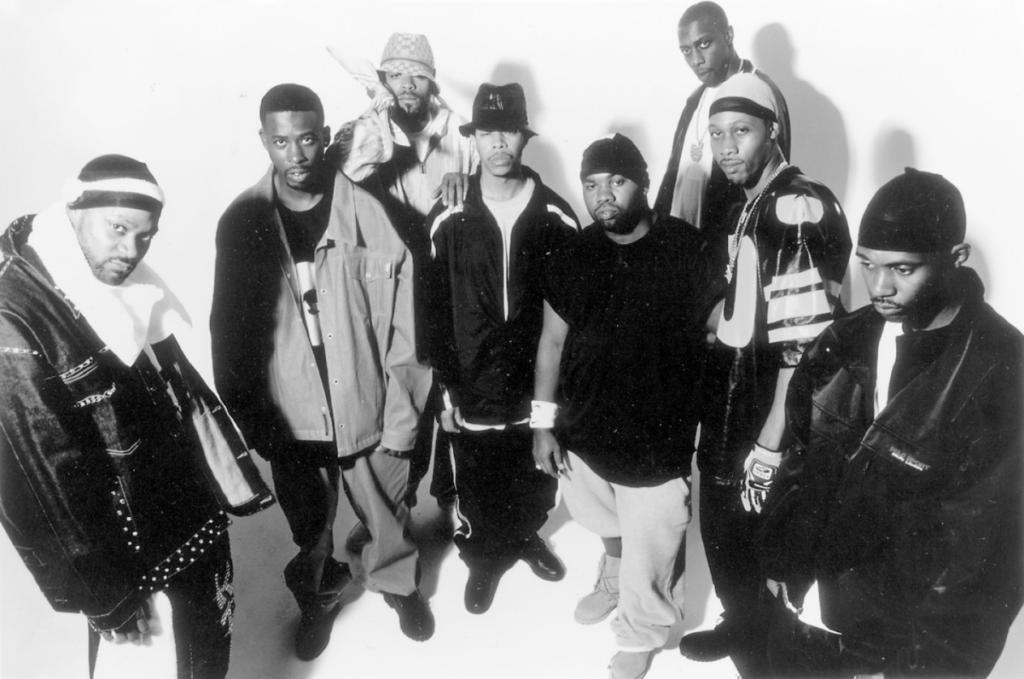 Fotografía histórica en blanco y negro del colectivo Wu-Tang Clan en 1993, mostrando a los integrantes originales con estética de la época: gorros de lana, chamarras de cuero y ropa deportiva. La imagen captura la actitud desafiante y el estilo visual del hip hop de Nueva York durante el lanzamiento de su disco debut '36 Chambers'.