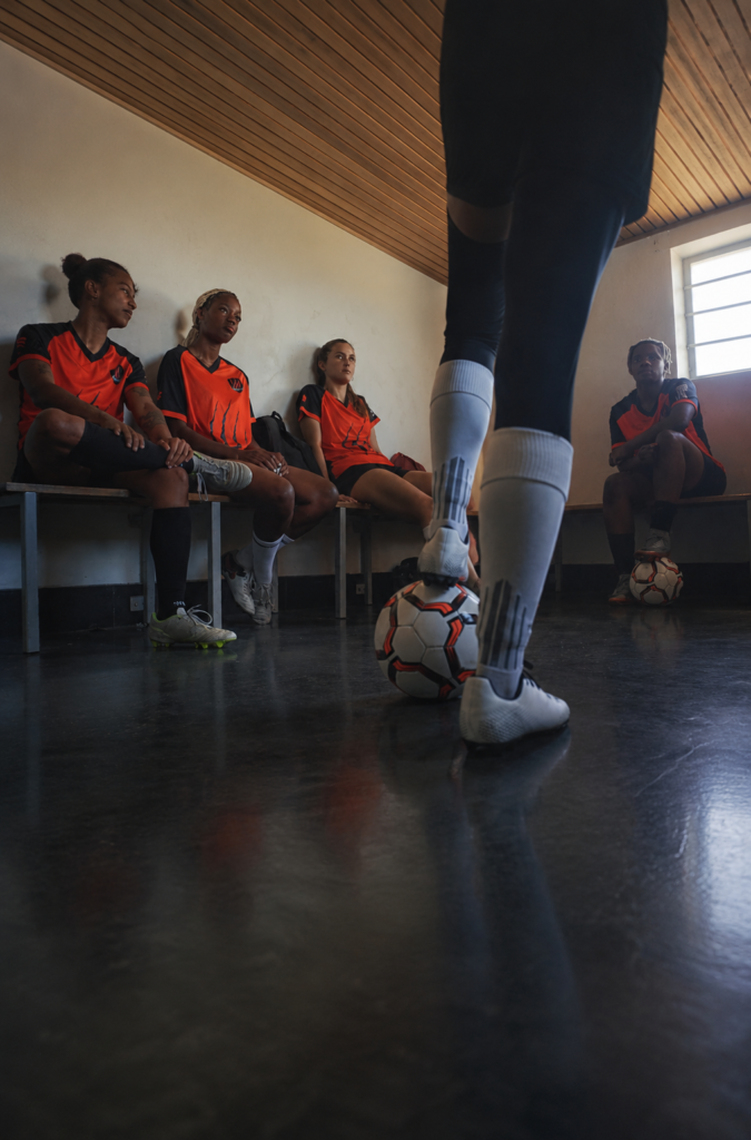 Equipo de fútbol femenino escucha atentamente la charla técnica de su entrenadora en el vestuario antes de iniciar un partido.