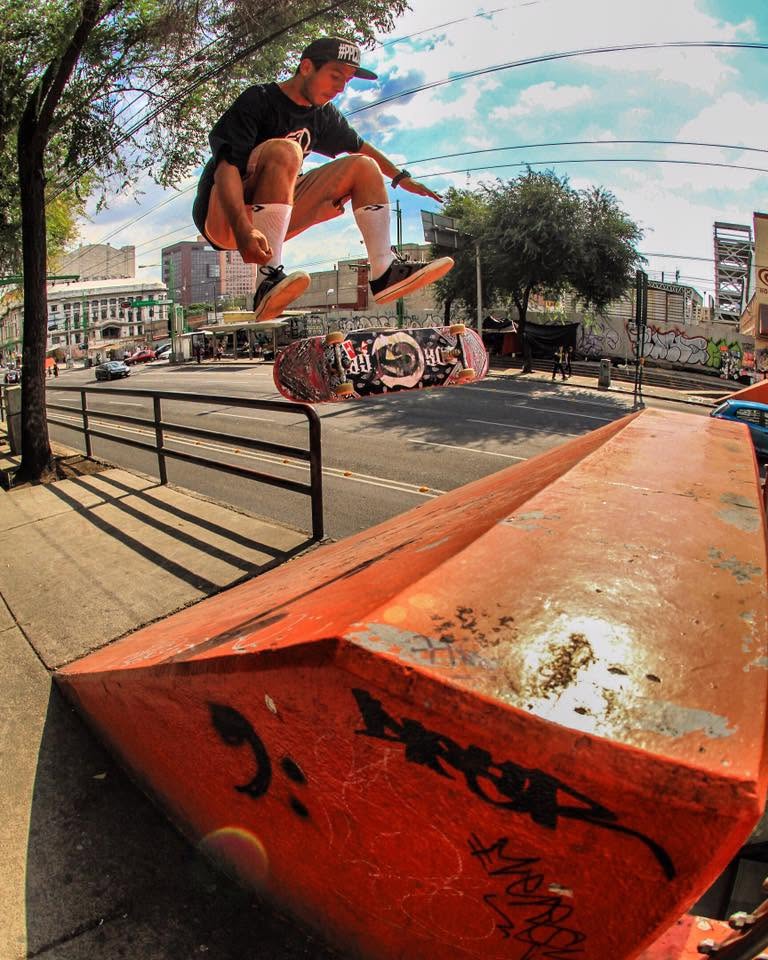El skater mexicano Brayan Coria vuela por el aire ejecutando un truco con su tabla Drop Skateboard sobre una rampa roja en las calles de la Ciudad de México.