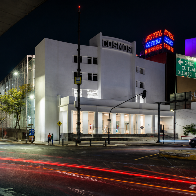 Fachada iluminada de noche del antiguo Cine Cosmos, actual FARO Cosmos, un edificio histórico de estilo Art Decó ubicado en la Calzada México-Tacuba en la Ciudad de México.