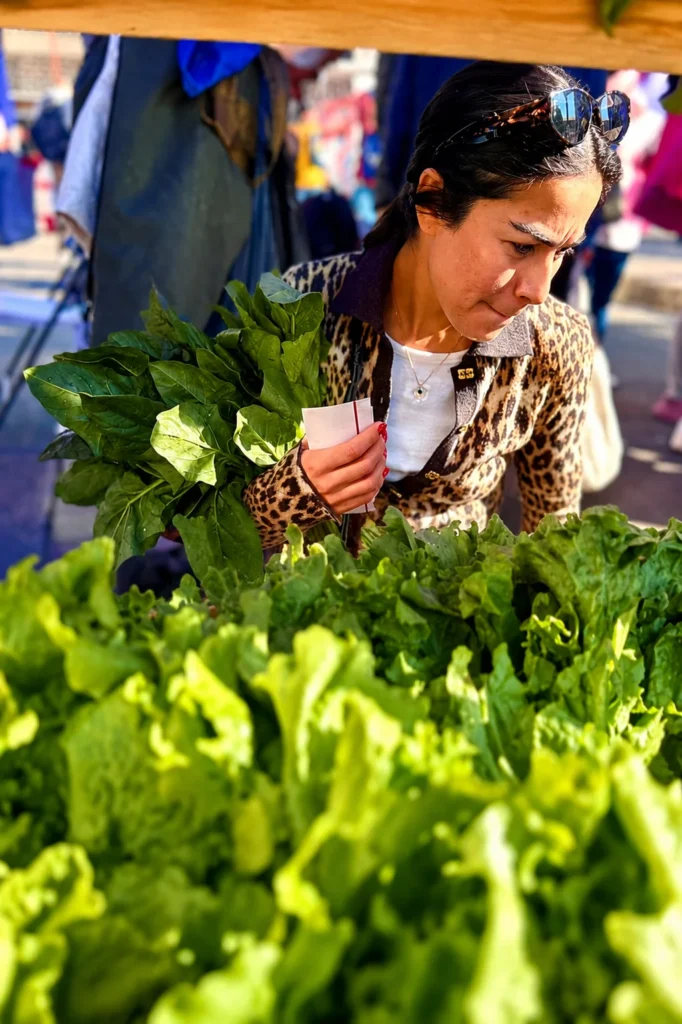Compradora seleccionando verduras frescas y hortalizas de temporada en un mercado agroecológico de la CDMX.