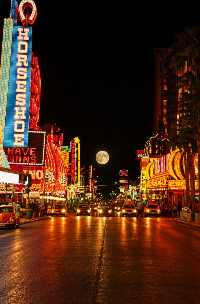 Fotografía antigua de la calle Fremont en Las Vegas por la noche durante los años 1980, destacando los letreros de neón brillantes del casino Binion's Horseshoe bajo la luna llena y autos de la época.