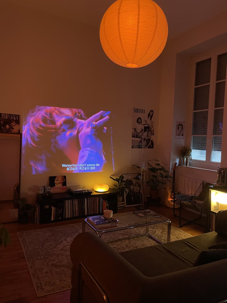 Sala de entretenimiento con proyector de cine en casa, luz ambiental cálida con lámpara de papel esférica y decoración juvenil de estilo grunge retro.