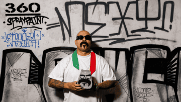 Letronero Mexicano: el espacio merecido del barrio en el arte Marco Osorio, artista de Letronero Mexicano, posa con lentes de sol y una estola tricolor de México frente a una pared con graffitis y caligrafía urbana en la Ciudad de México