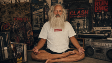 Rick Rubin y la caída del falso gurú: creatividad, tecnología y The Way of Code El productor musical Rick Rubin meditando en posición de loto con una playera clásica Box Logo de Supreme, rodeado de portadas de vinilos icónicos de hip-hop y metal.