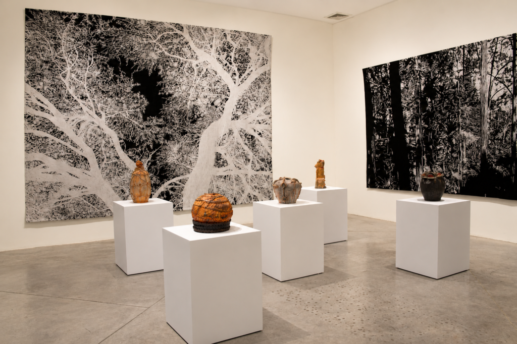 Vista de la exposición Toledo + Hendrix en la Galería de Arte Mexicano, con tapices botánicos de Jan Hendrix y cerámicas de Francisco Toledo.