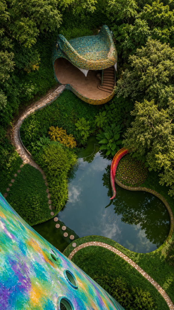 Vista aérea del Nido de Quetzalcóatl en Naucalpan, México, mostrando la cabeza de la serpiente gigante hecha de azulejos y un estanque rodeado de selva, obra de arquitectura orgánica de Javier Senosiain.
