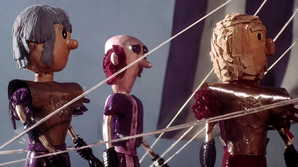 Tres marionetas articuladas de madera de soldados griegos a bordo de un barco en una escena a color de la película mexicana de stop motion La Odisea de los Muñecos de 1975.