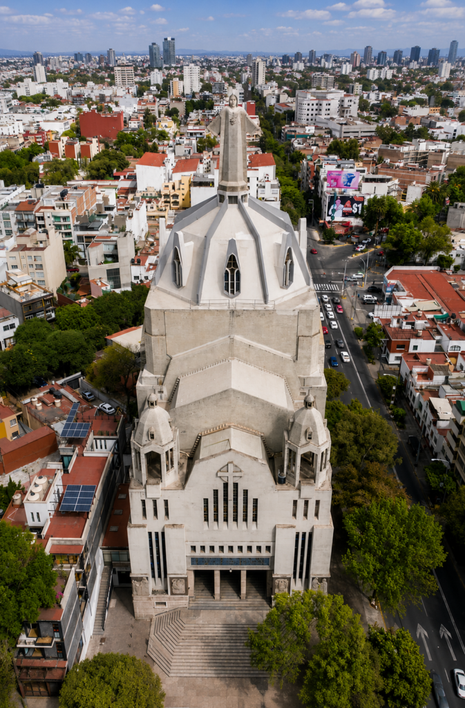 Vista aérea con dron de la fachada de hormigón y cúpula poliédrica de la Parroquia del Purísimo Corazón de María en la Ciudad de México, destacando influencias de la arquitectura neogótica y Art Déco.